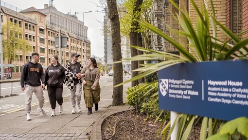 Four students walking outside Cardiff campus 