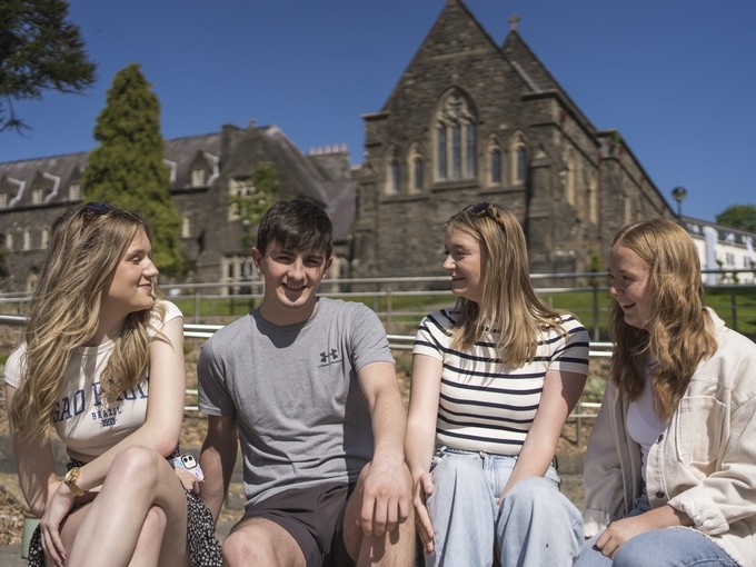 students outside with carmarthen campus as a backdrop 