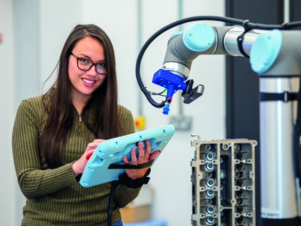 Student smiling and operating machinery 