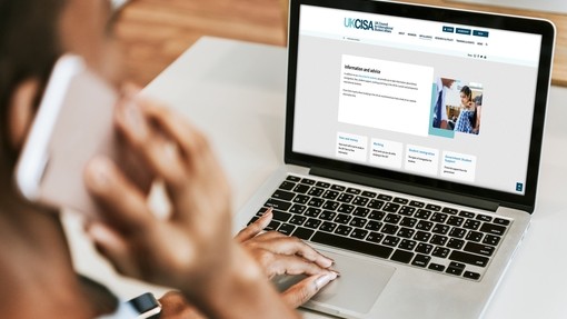 Person on the phone and viewing the UKCISA site