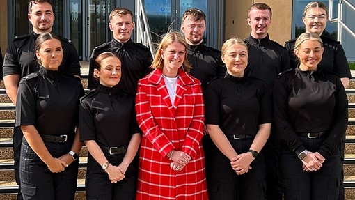 Bronwen Williams stands in the centre of a group of ten black-clad new police officers.
