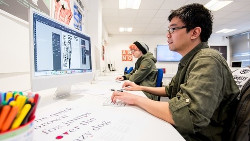 A student uses an Apple Mac with a widescreen monitor. 