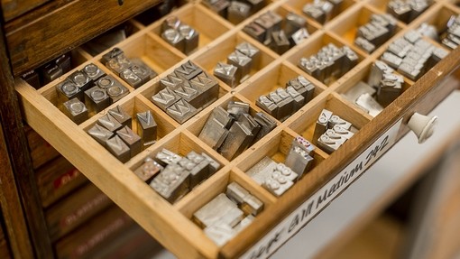 A type case tray holding metal typeface blocks in different compartments.