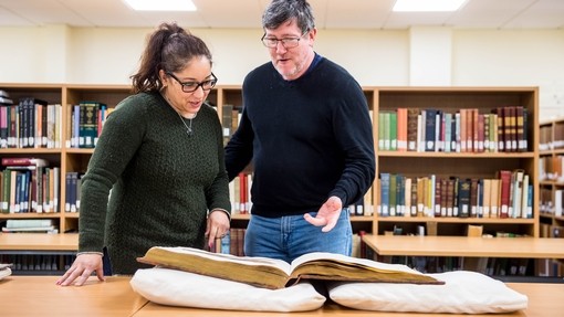 Students standing over book